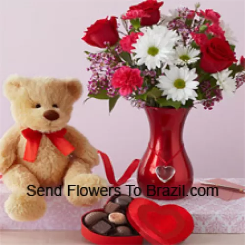 Rose rosse e Gerbere bianche con alcune felci in un vaso di vetro insieme a un carino orsacchiotto marrone alto 12 pollici e una scatola di cioccolatini importati