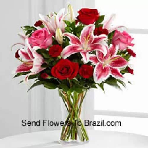 Roses rouges et roses avec des lys roses et des remplissages saisonniers dans un vase en verre