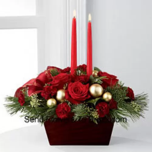 An exquisite display of holiday beauty to add warmth and cheer to their special celebrations. Rich red roses and burgundy mini carnations are set to impress surrounded by lush holiday greens, seeded eucalyptus, gold glass balls and a gold-edged red ribbon arranged elegantly around two red taper candles. Presented in a chocolate brown bamboo container, this centerpiece will usher in joy and goodwill with each treasured bloom (Please Note That We Reserve The Right To Substitute Any Product With A Suitable Product Of Equal Value In Case Of Non-Availability Of A Certain Product)